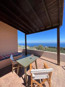 a table and chairs on a patio with a view of the ocean at Anatolí Village House in Epáno Kefalás