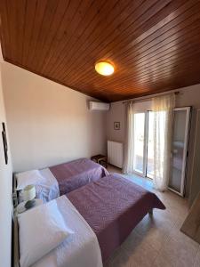 sypialnia z 2 łóżkami i drewnianym sufitem w obiekcie Anatolí Village House w mieście Epáno Kefalás