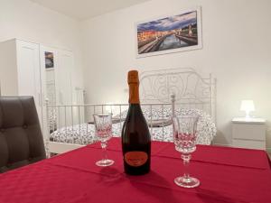een fles wijn zittend op een tafel met twee glazen bij Casa Roma rooms& apartmens in Padua