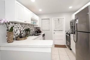 uma cozinha com armários brancos e um frigorífico de aço inoxidável em Beachy/Rustic home for 6 ppl em Dania Beach