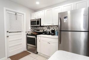 uma cozinha com armários brancos e um frigorífico de aço inoxidável em Beachy/Rustic home for 6 ppl em Dania Beach