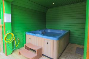 a hot tub in a green room with a stool at Retreat to Oak Tree Lodge - A Romantic Getaway in Devon's Finlake Resort & Spa in Chudleigh