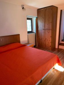 1 dormitorio con 1 cama con colcha de color naranja en Casa a Miazzina en Miazzina