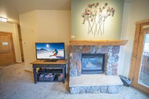 a living room with a tv and a fireplace at Arapahoe Lodge 8119 in Keystone