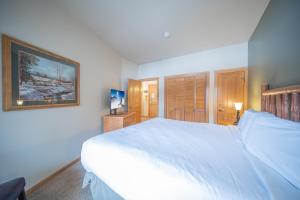 a bedroom with a large white bed and a television at Arapahoe Lodge 8119 in Keystone
