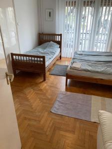 Habitación con 2 camas, suelo de madera y ventanas. en Cargo Rooms and Apartment, en Budapest