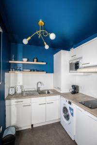 a kitchen with white cabinets and a blue wall at Experience olympique proche Paris in Le Plessis-Robinson