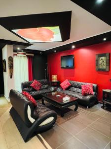uma sala de estar com mobiliário de couro preto e uma parede vermelha em Dolls Hotel By Eurostars em Jounieh
