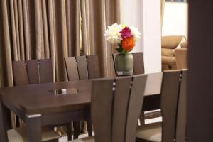 a table and chairs with a vase of flowers on it at Spacious 3BR Apartment in Ghana Jeffston Court Prime Stay in Accra in Accra