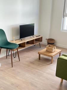 ein Wohnzimmer mit einem TV und einem grünen Stuhl in der Unterkunft Apartamento a estrenar en Ribamontán al Mar in Hoznayo