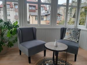 two chairs and a table in a room with windows at Berni's home Apartament z tarasem in Sopot