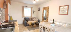uma cozinha e sala de estar com uma mesa e um sofá em Gîte - Les Pivoines Les Jardins de Kerellec 20min de la mer 4 à 6 personnes terrasse em Plouvorn