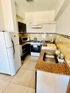 a kitchen with a white refrigerator and a sink at El Cairo 10 in Puerto Madryn +6 photos