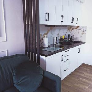 Una cocina con gabinetes blancos y una encimera negra. en BaltikApart, en Hel