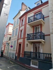 - un bâtiment rouge et blanc avec balcon dans une rue dans l'établissement Home St. Germain, à Trouville-sur-Mer