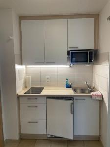 a kitchen with white cabinets and a sink and a microwave at Geschäfts- und Ferienwohnung 111 in Bad Urach