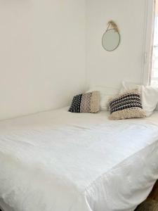 a white bed with pillows on top of it at Bord de Mer et Sérénité Bormes-les-Mimosas in Bormes-les-Mimosas