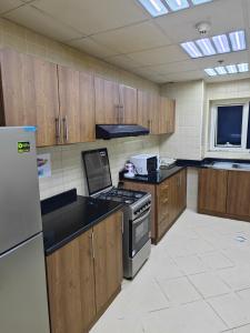 een keuken met houten kasten en een fornuis met oven bij Pretty Room in Shared Apartment in Ajman 