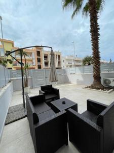 a patio with chairs and a palm tree on a balcony at Cielo Stellato in Polignano a Mare