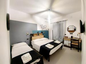 a bedroom with two beds and a desk with a mirror at Don Mario Aparthotel & Rooms in Marina di Camerota