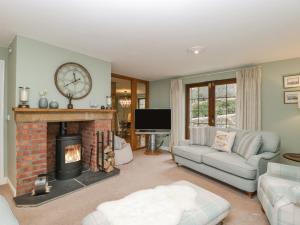 a living room with a fireplace and a clock on the wall at Sundowner Cottage in Axminster