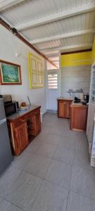 a large kitchen with wooden cabinets and a large tile floor at le temps d'une île in Grand-Bourg