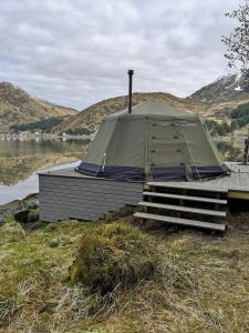 a tent sitting on a dock next to a body of water at FLO Lofoten eco glamping in Valberg