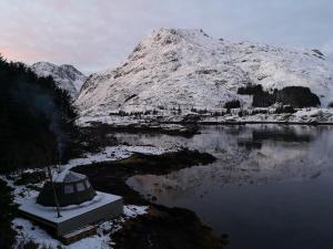a snow covered mountain next to a body of water at FLO Lofoten eco glamping in Valberg
