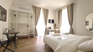 a white bedroom with a bed and a table at Fortuna Guest House in Siracusa