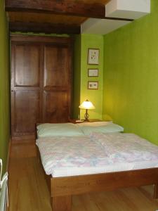 Kostanjevica na KrkiにあるApartmaji Žolnirの緑の壁のベッドルーム1室、ベッド1台(ランプ付)