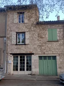 - un bâtiment en briques avec des portes et des fenêtres vertes dans l'établissement Maison paisible avec parking, à Montpezat-de-Quercy