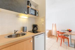 una pequeña cocina con fregadero y mesa en Appart'City Classic Aix-en-Provence - La Duranne, en Aix-en-Provence
