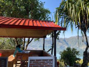 Eine Frau, die an einem Tisch unter einem Dach sitzt. in der Unterkunft Nice View Cottage in Pokhara