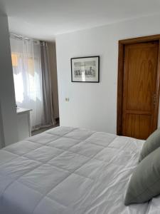 una camera da letto con un grande letto bianco e una porta in legno di Apartamento Ilusión a Corralejo
