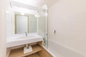 a white bathroom with a sink and a shower at Appart'City Classic Aix-en-Provence - La Duranne in Aix-en-Provence