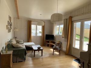 salon z kanapą i stołem w obiekcie Charmante Maison de Campagne en Pierres et Bois w mieście Sartilly