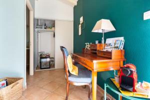 einen Schreibtisch mit einem Stuhl und einen Tisch mit einer Lampe in der Unterkunft La Chambre Verte in Cazères