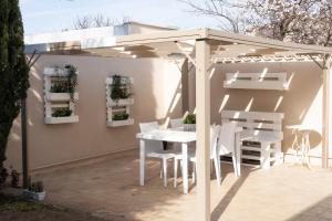 a white pergola on a patio with a table and chairs at Emotions in Fiumicino