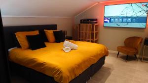 una camera da letto con un letto giallo con una TV a schermo piatto di Relaxed Luxe "Boszichthuisje" met Jacuzzi Bospark Ijsselheide Hattemerbroek a Hattemerbroek