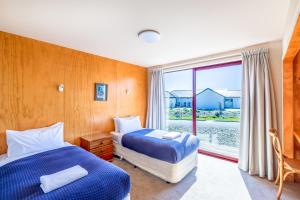 two beds in a room with a window at Castle Hall - Lake Tekapo in Lake Tekapo
