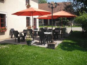 un patio con mesas, sillas y sombrillas en Auberge de la Motte, en Les Combes