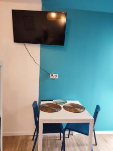 una mesa con sillas y una TV en una pared azul en Studio cosy avec parking, en Brest