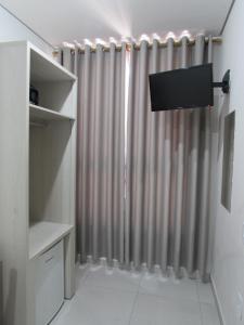 ein Badezimmer mit Duschvorhang und Fernseher in der Unterkunft Hotel Salomão - Próximo a 25 de Março, Bom Retiro, Brás e Rua Santa Efigênia, a 2 minutos do Mirante Sampa Sky e pista de Skate Anhangabaú in São Paulo