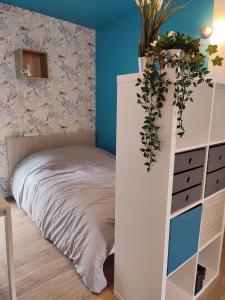 Un dormitorio con una cama y un tocador blanco con una planta. en Studio cosy avec parking, en Brest