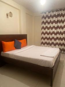 a bedroom with a bed with orange and black pillows at Magnolia guesthouse in Kampala