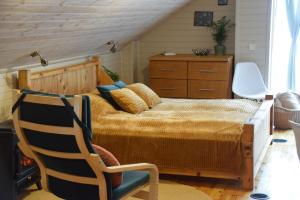 a bedroom with a large bed and a chair at Čučumuiža in Ķimale