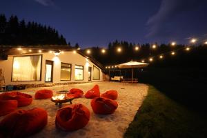 un bâtiment avec des poufs rouges et un parapluie la nuit dans l'établissement NICA Chalet, à Fundata