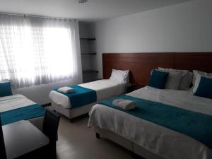 Habitación de hotel con 2 camas y ventana en hotel casa lamay, en Bogotá