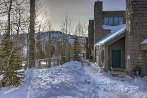 a snow covered yard next to a house with a green door at Cozy Mountain Getaway - 2 Bedroom + Loft (Pet-Friendly!) in Brian Head