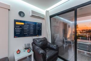 ein Wohnzimmer mit einem Ledersessel und einem Fenster in der Unterkunft Alexis Apartments - Modern 2-bedroom with swimming pool in Paphos City